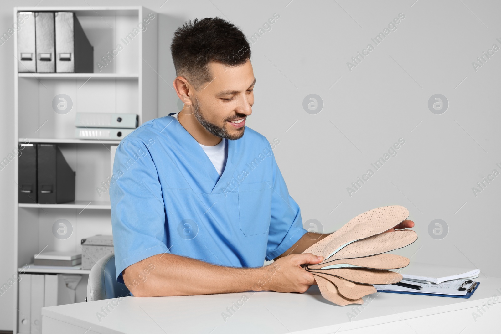 Photo of Handsome male orthopedist showing insoles in hospital