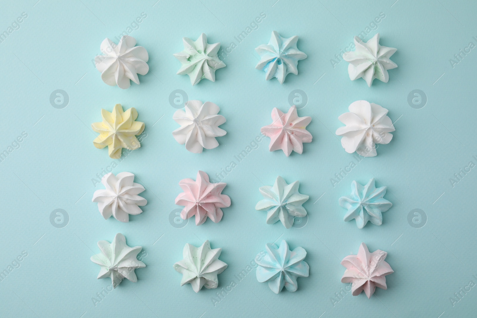 Photo of Delicious meringue cookies on light blue background, flat lay