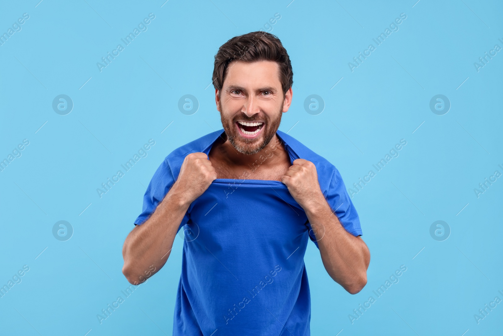 Photo of Emotional sports fan celebrating on light blue background