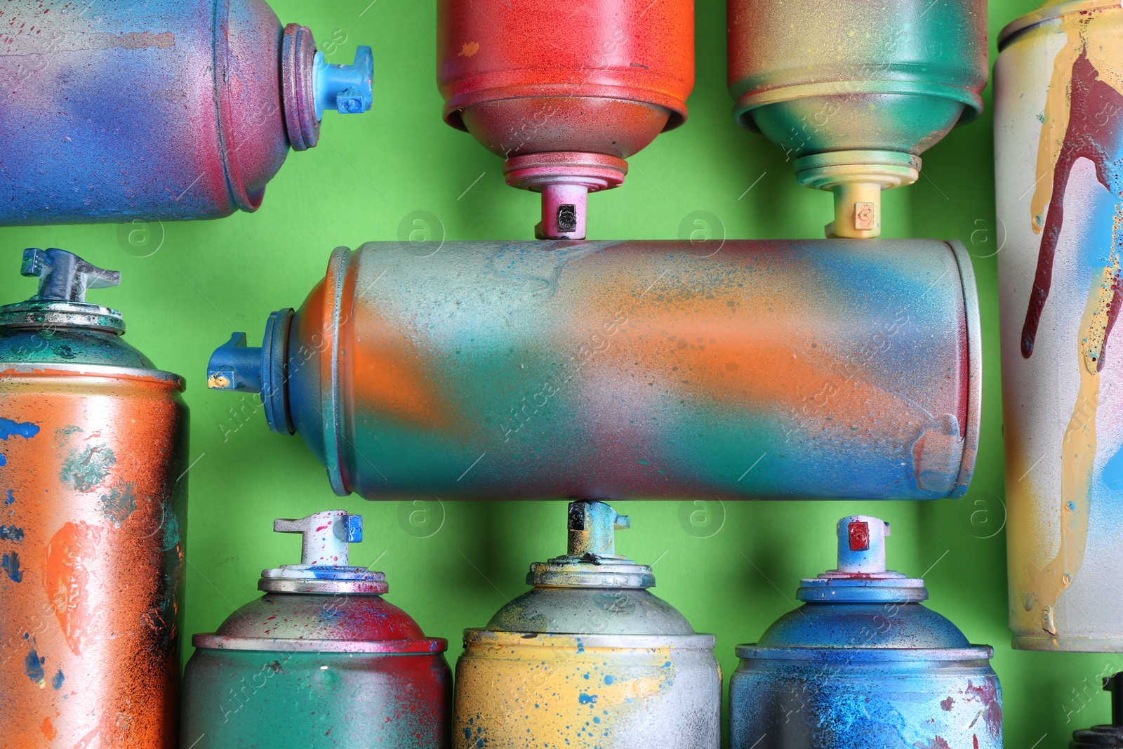 Photo of Many spray paint cans on green background, flat lay