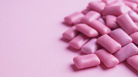 Heap of tasty sweet chewing gums on pink background, closeup. Space for text