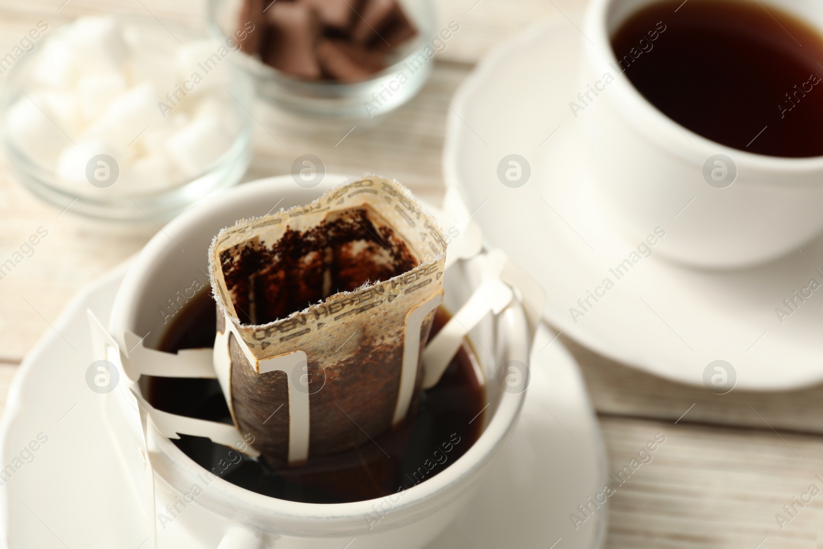 Photo of Cup with drip coffee bag on white table, closeup