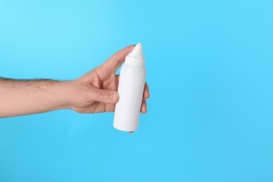 Man holding nasal spray on light blue background, closeup. Space for text