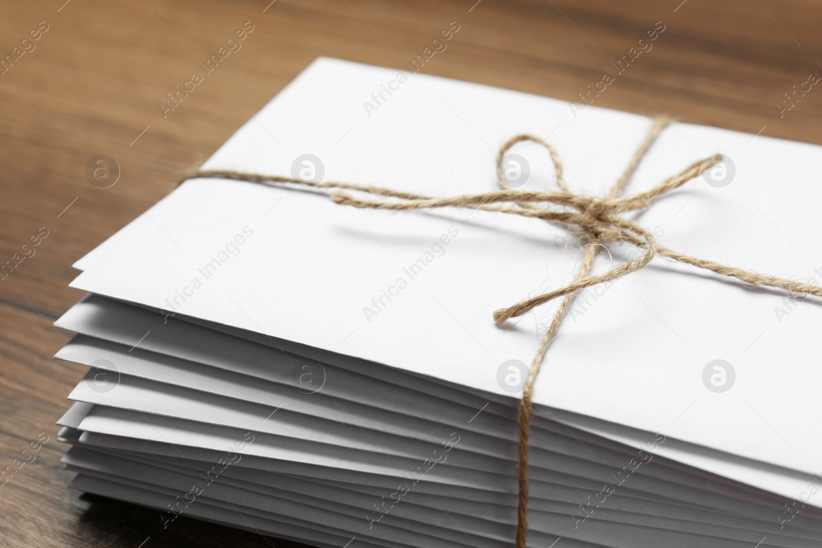 Photo of Stack of letters tied with twine on wooden table, closeup