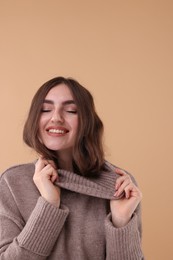 Photo of Portrait of beautiful young woman in warm sweater on brown background