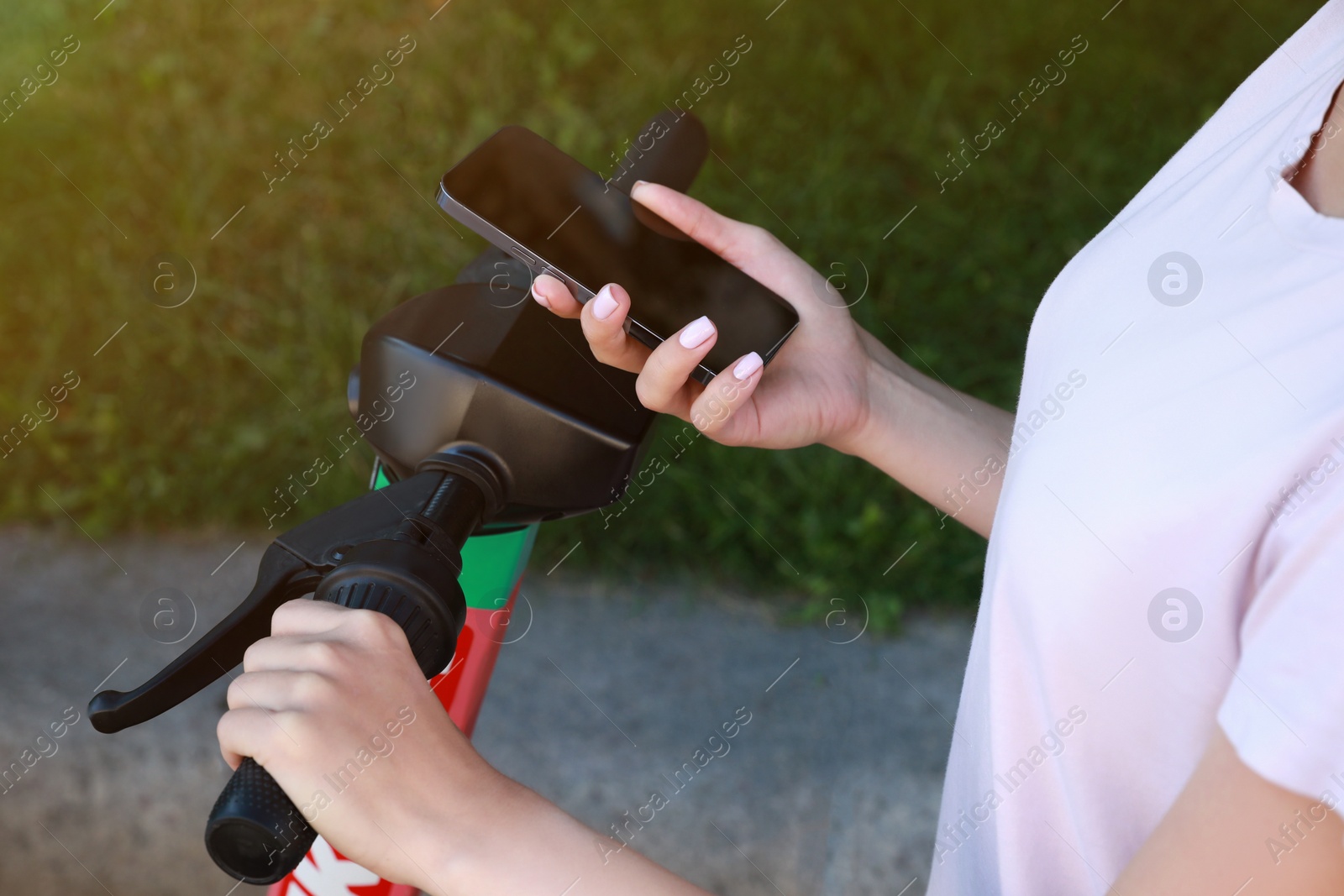 Photo of Woman using smartphone to pay and unblock electric kick scooter outdoors, closeup