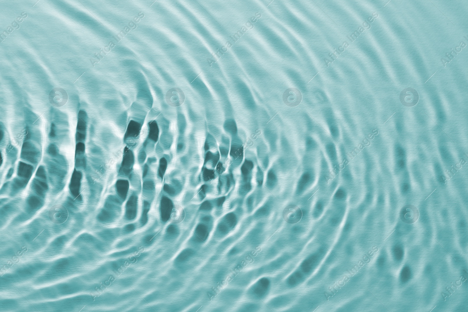 Image of Rippled surface of clear water on light blue background, closeup