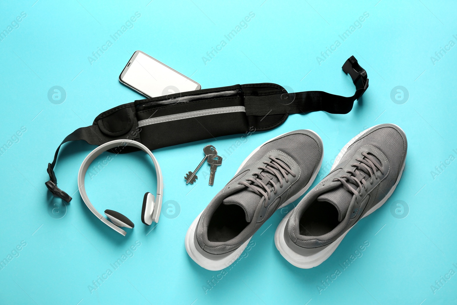 Photo of Flat lay composition with stylish black waist bag on light blue background