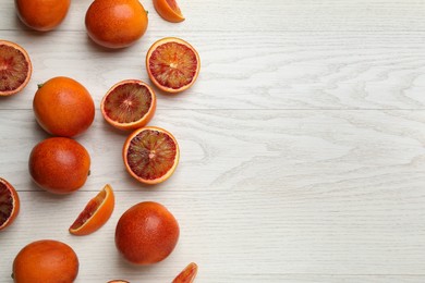 Photo of Many ripe sicilian oranges on white wooden table, flat lay. Space for text