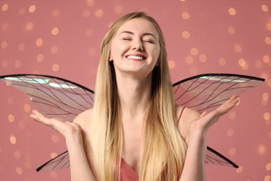 Photo of Beautiful girl in fairy costume with wings on pink background