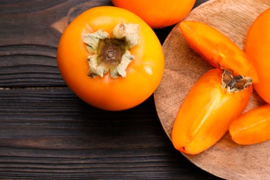 Photo of Delicious ripe persimmons on wooden table, top view. Space for text