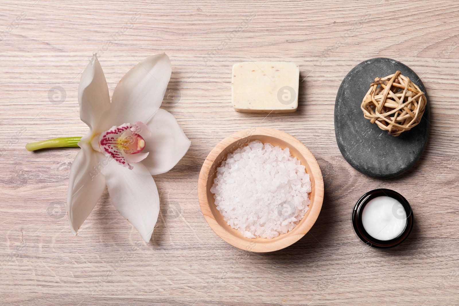 Photo of Flat lay composition with spa products and beautiful flower on light wooden table