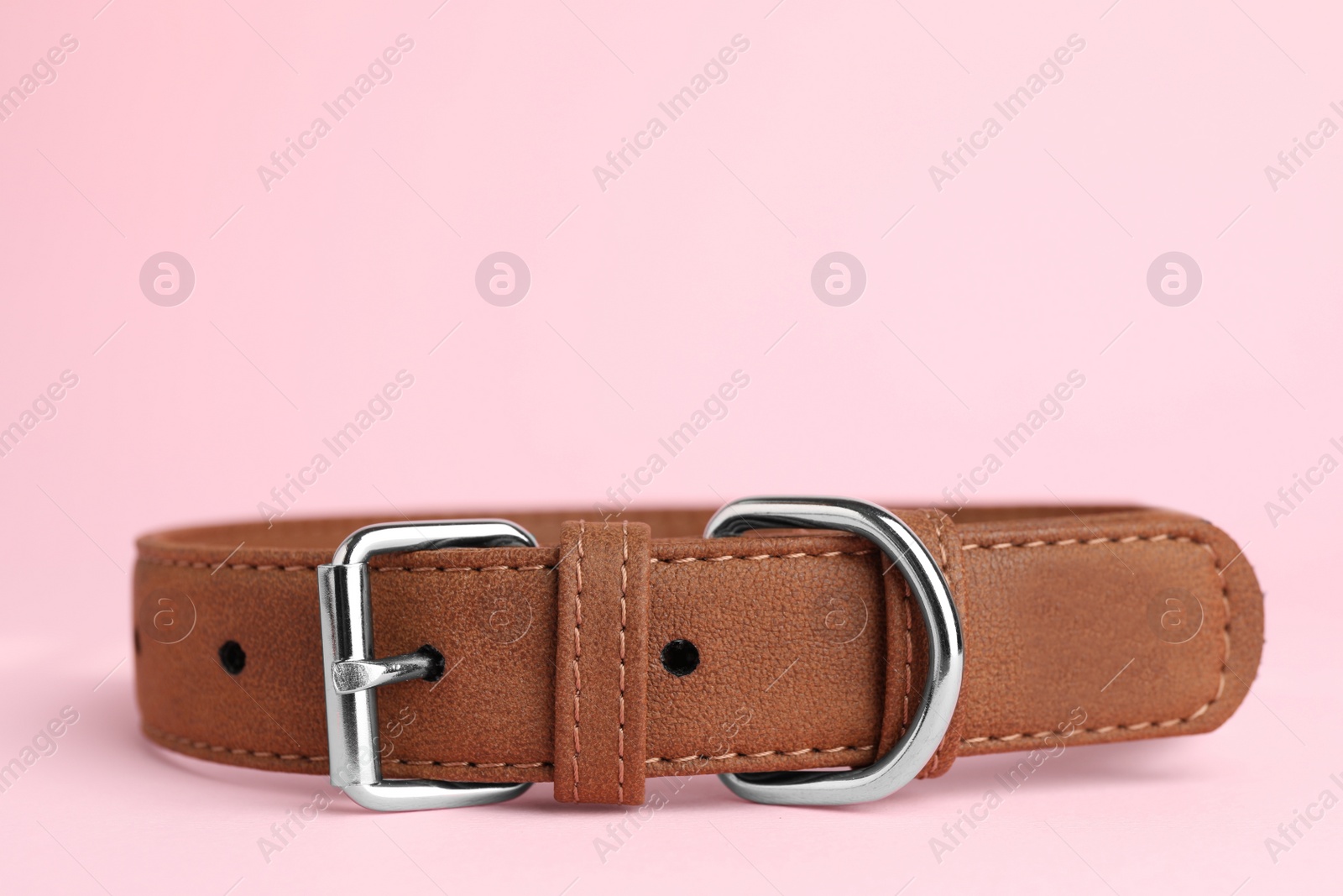 Photo of Brown leather dog collar on pink background, closeup. Space for text