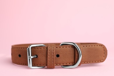 Photo of Brown leather dog collar on pink background, closeup. Space for text