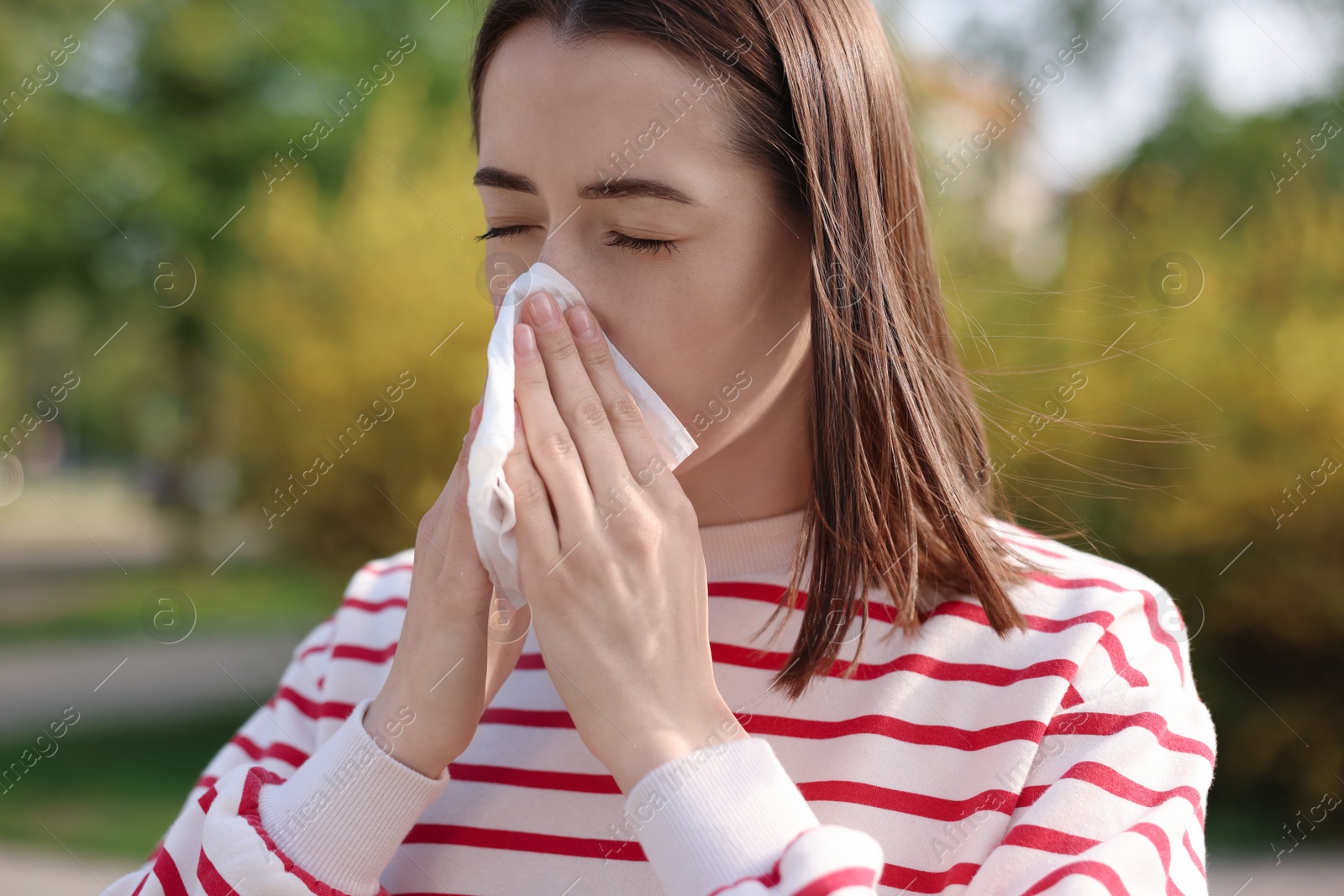 Photo of Woman with napkin suffering from seasonal allergy outdoors