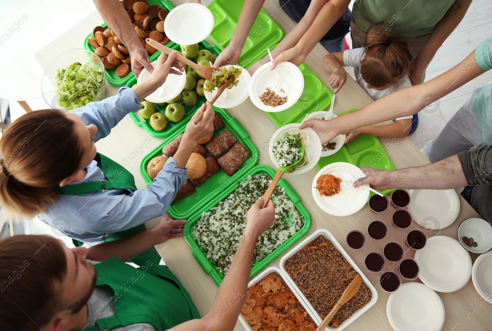 Photo of Volunteers serving food for poor people at table, top view