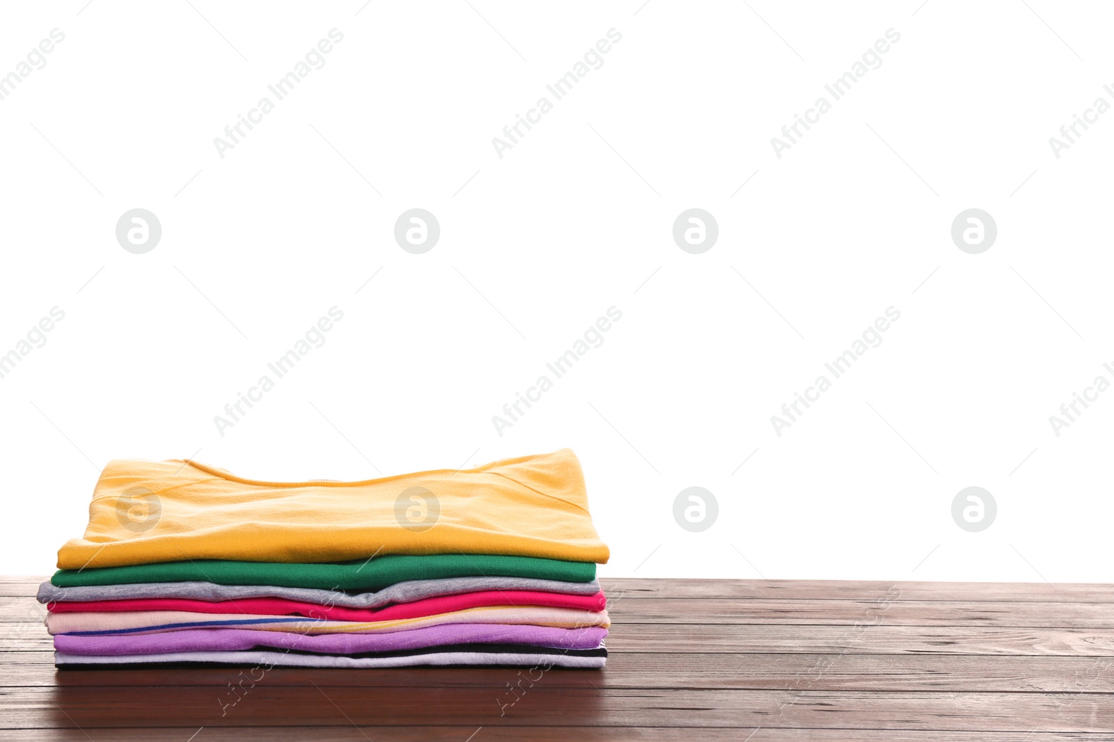 Photo of Pile of ironed clothes on table against white background. Space for text