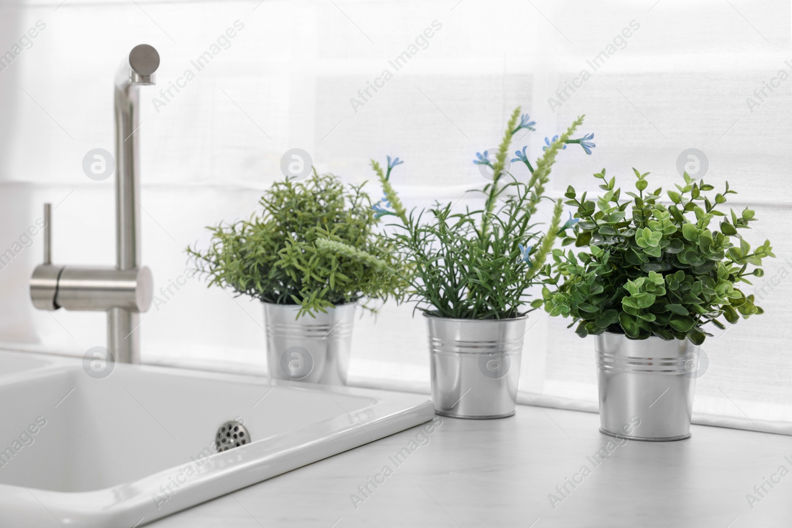 Photo of Different potted artificial plants on countertop in kitchen. Home decor