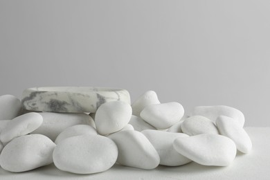 Presentation for product. Stone podium and white pebbles on table against light background. Space for text