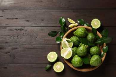 Photo of Whole and cut ripe bergamot fruits with green leaves on wooden table, flat lay. Space for text