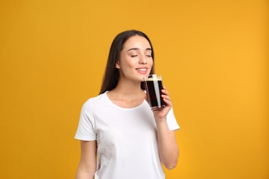 Photo of Beautiful woman with cold kvass on yellow background. Traditional Russian summer drink