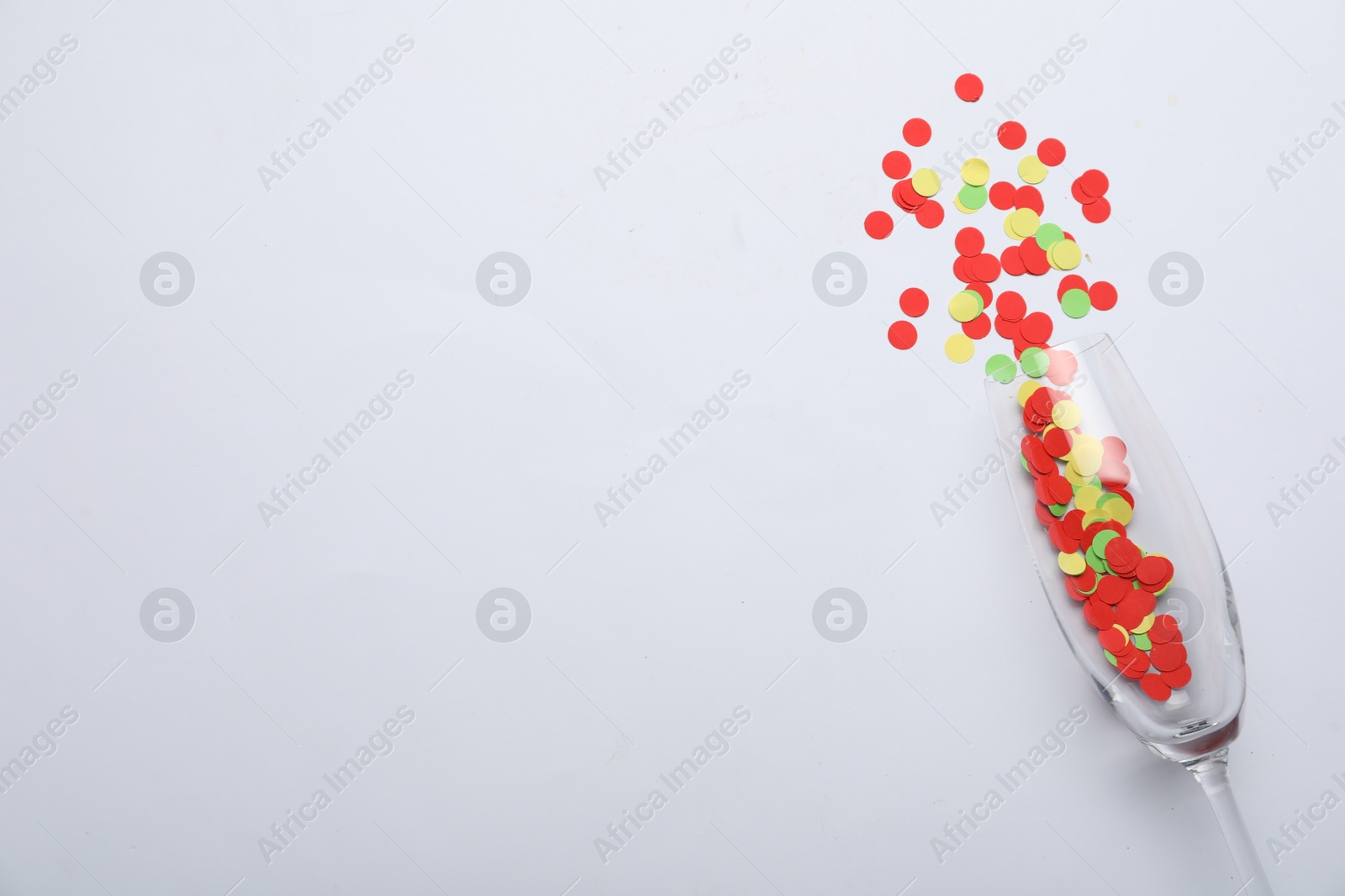 Photo of Flat lay composition with confetti and champagne glass on light background. Space for text