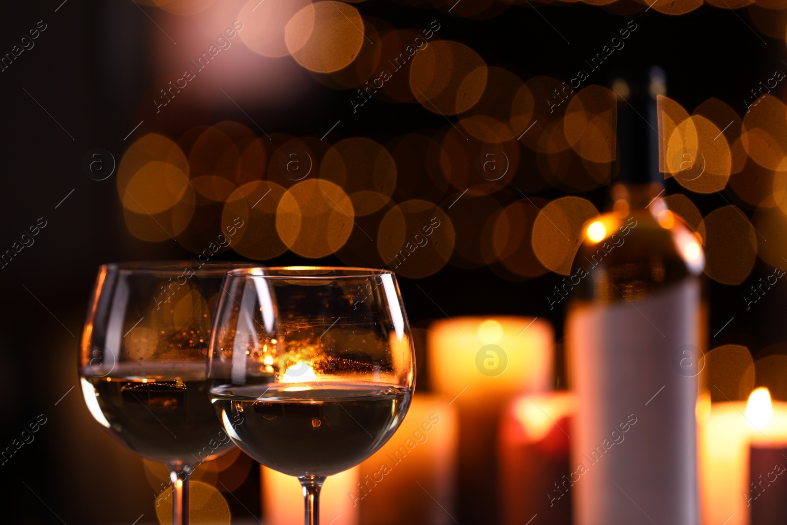 Photo of Glasses of wine and blurred view of burning candles on background
