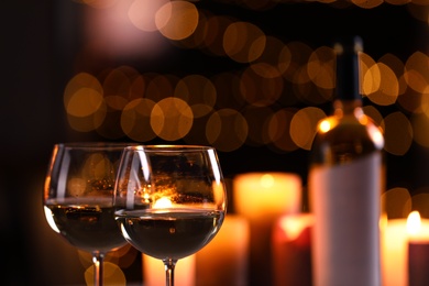 Photo of Glasses of wine and blurred view of burning candles on background