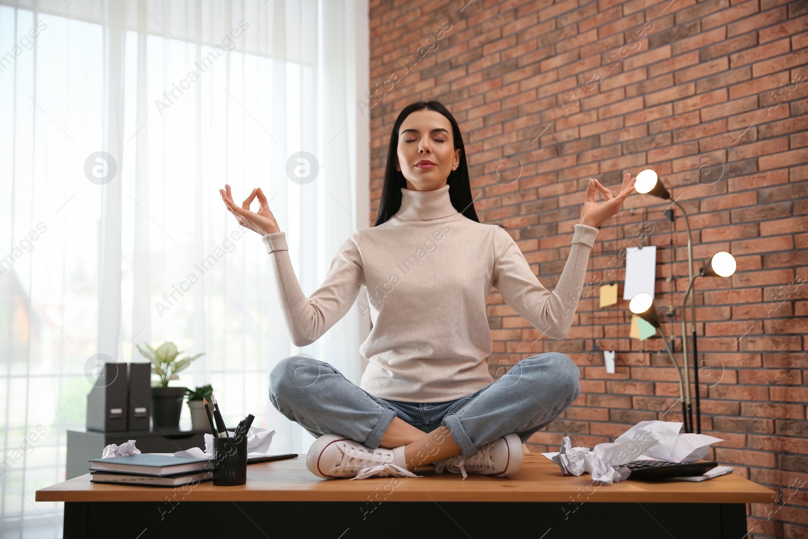 Photo of Young woman meditating at workplace. Stress relief exercise