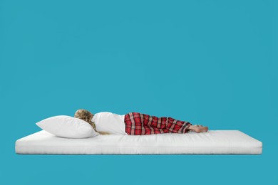 Little girl sleeping on comfortable mattress against light blue background, space for text