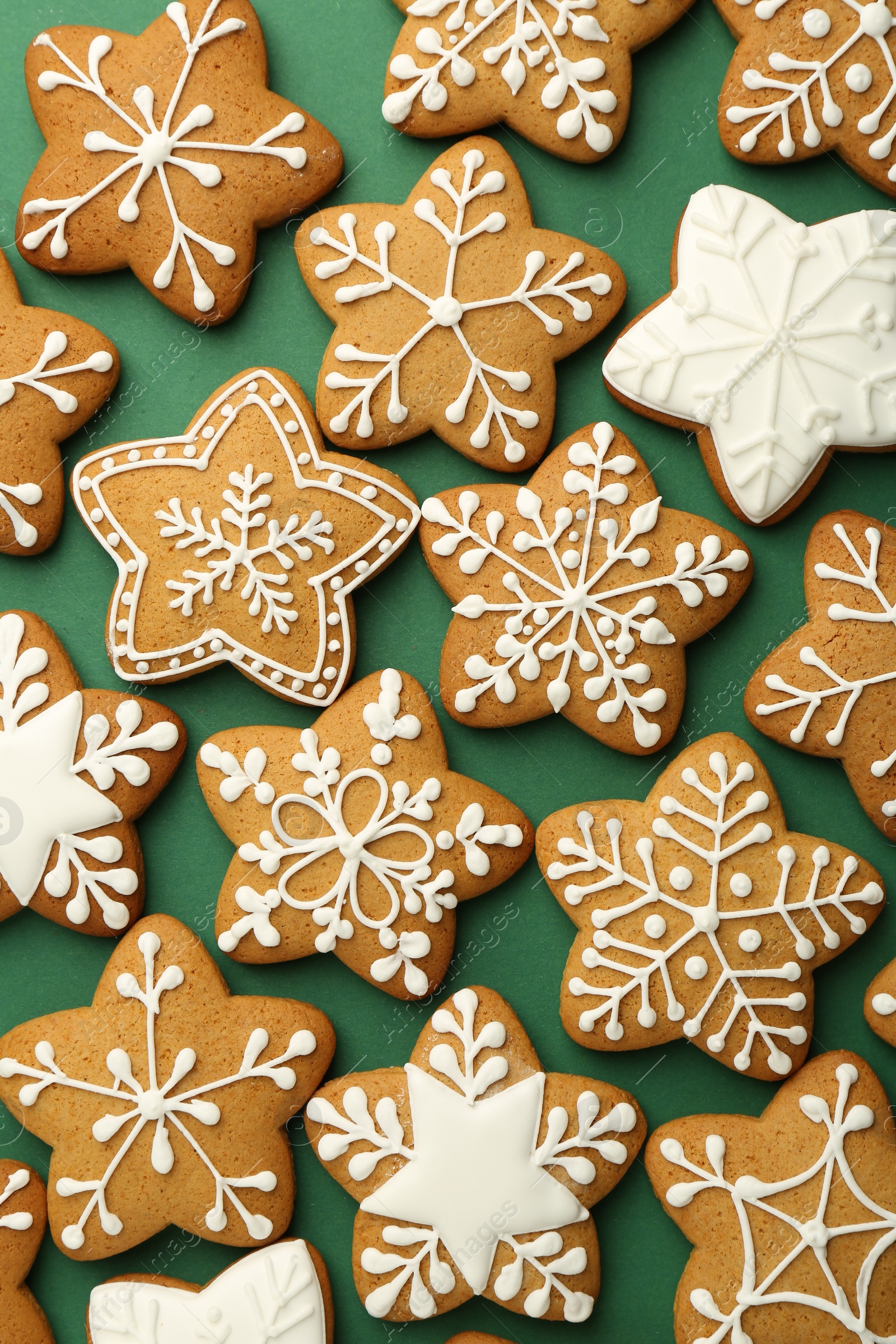 Photo of Tasty Christmas cookies with icing on green background, flat lay