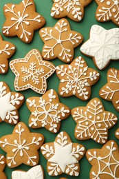 Photo of Tasty Christmas cookies with icing on green background, flat lay