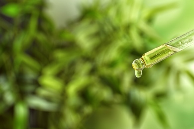 Photo of Dropper with essential oil on blurred background