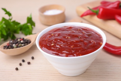 Photo of Bowl of hot chili sauce and ingredients on table, closeup