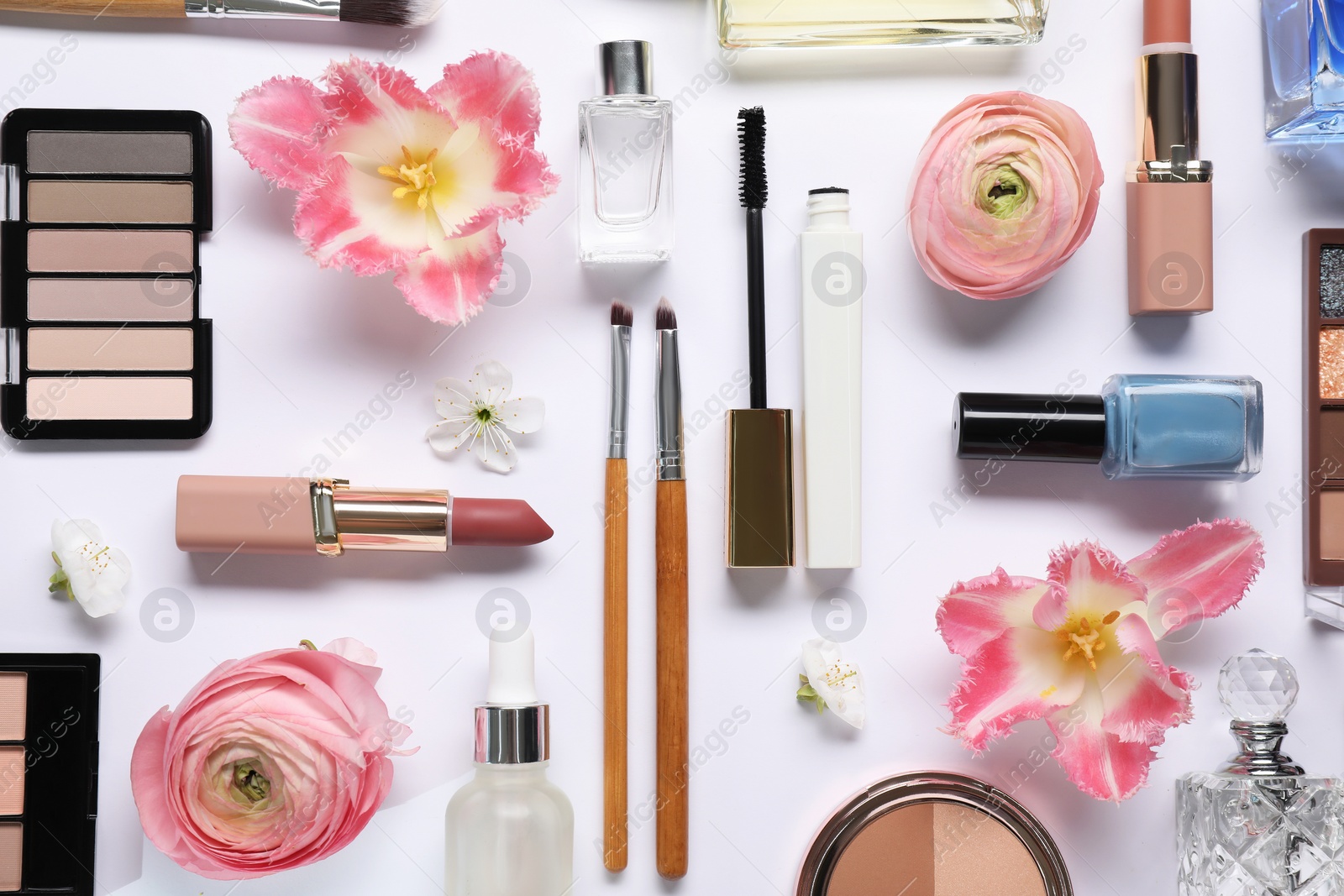 Photo of Flat lay composition with different makeup products and beautiful spring flowers on white background