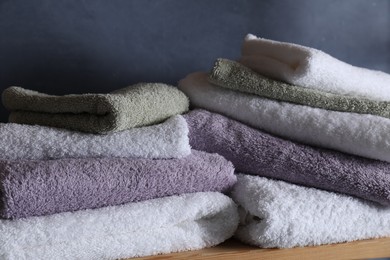 Photo of Stacked soft towels on wooden shelf indoors, closeup