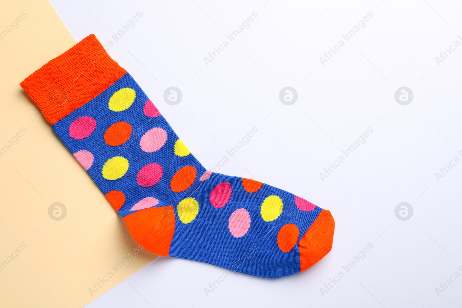 Photo of New sock with pattern on color background, top view. Space for text