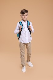 Back to school. Cute boy with backpack on beige background