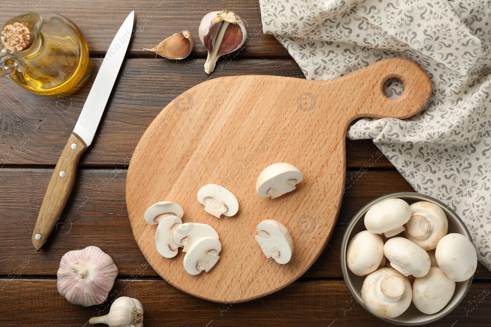 Photo of Cutting board with mushrooms and knife on wooden table, flat lay