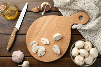 Cutting board with mushrooms and knife on wooden table, flat lay