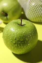 Photo of Ripe apple with water drops on light green background, closeup