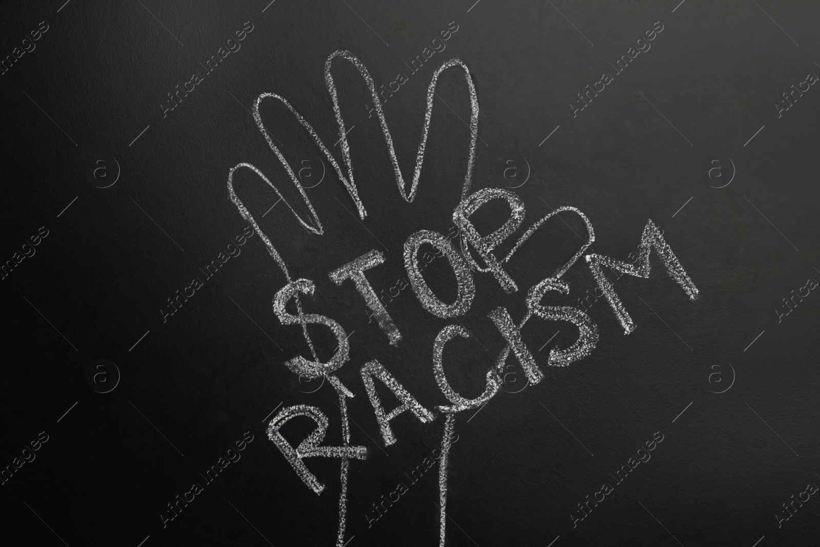 Photo of Chalked inscription Stop Racism and raised hand on blackboard