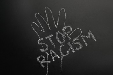 Photo of Chalked inscription Stop Racism and raised hand on blackboard