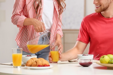 Happy young couple having breakfast at table in room