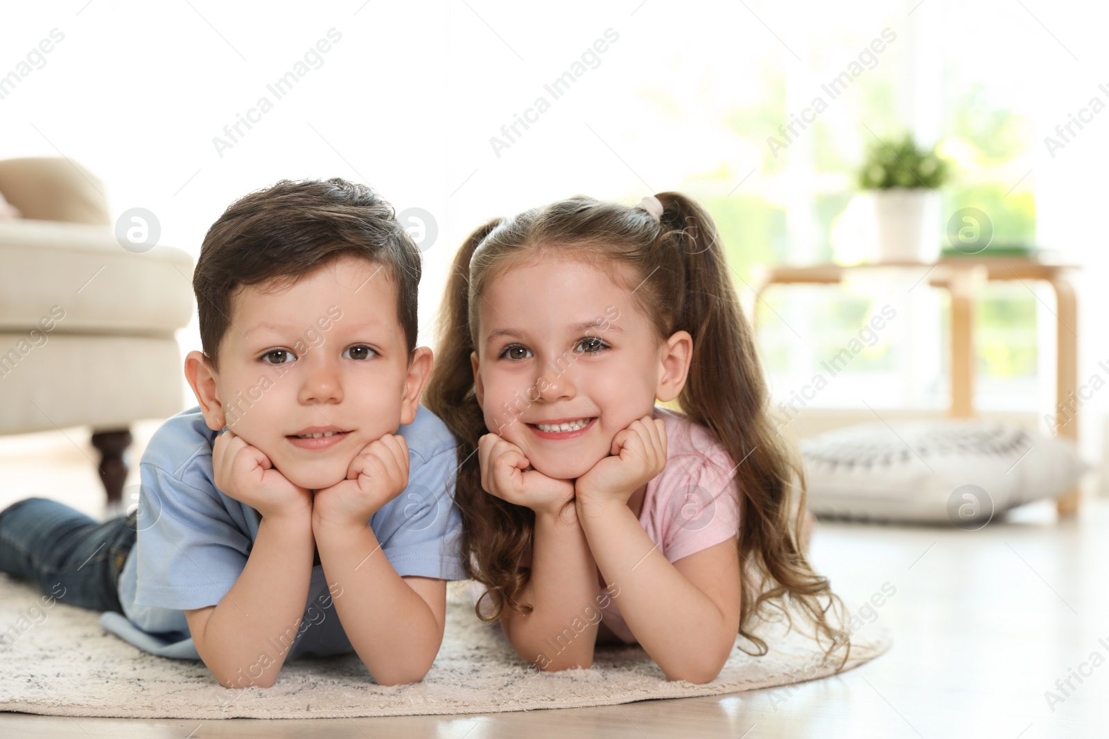 Photo of Cute children lying on carpet in living room