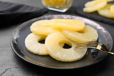 Photo of Tasty canned pineapple rings served on black table table, closeup