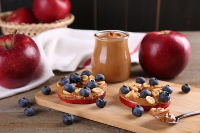 Photo of Slices of fresh apple with peanut butter and blueberries on wooden table