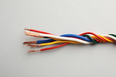 Photo of Many twisted electrical wires on light background, closeup