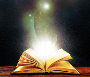 Image of Magic light emanating from open old book on table