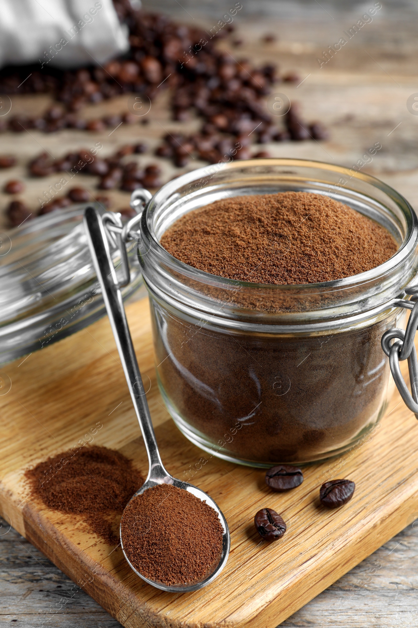 Photo of Glass jar of instant coffee and spoon on wooden table, closeup